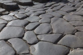 Close-up of large grey smooth and worn lava stones in a street at the ancient ruins of Pompeii,