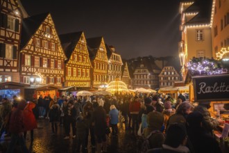 People gather on a Christmas-lit market square with historic buildings, Christmas market Calw,