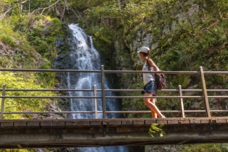 A woman on a wooden bridge at the Todtnau waterfall in the Black Forest in Germany
