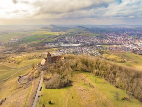 Aerial view of the castle with surrounding dense forests and a neighbouring village under a cloudy