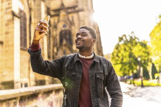 Happy african man walking along the city taking photos under the sunset