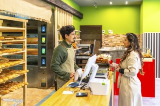 Elegant latin woman talking to salesman in a modern and artisan bakery