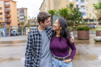 Happy multiethnic couple shares a joyful moment outdoors, embracing and smiling at each other,