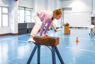 Redhead student practicing gymnastics on pommel horse, showing balance and coordination in school