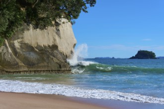 Breaking waves with spray in front of mighty cliffs by the sea, Cathedral Cove, Hahei, Coromandel