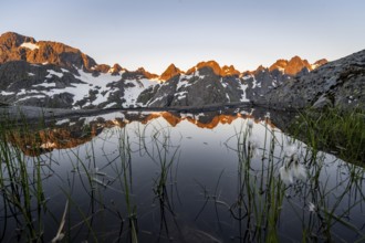 Rocky mountain peaks with reflection, small pond with cotton grass in moor landscape at Trollfjord
