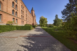 New town hall, brick building, architectural style neo-Gothic, former barracks, hedge, trees, blue
