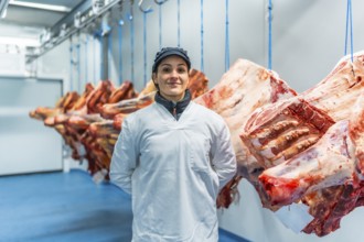 Three quarter length frontal portrait of a proud and happy woman butcher in a meat processing