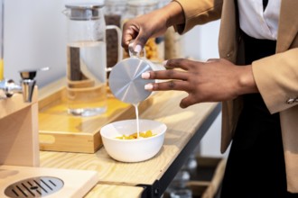 Businesswoman pouring milk into a bowl of cereal, enjoying breakfast during a business trip