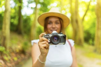 Portrait with selective focus on the camera in hands of a young female caucasian photographer in