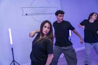 Group of young dancers practicing a modern choreography in a dance studio with neon lights