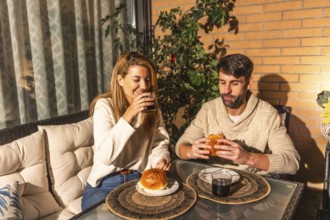 Smiling man and woman enjoying burgers and beverages on a cozy terrace, creating a warm and