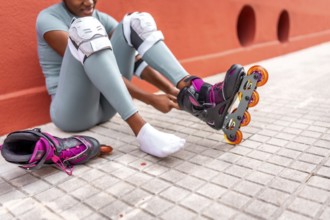 Cropped photo of part of an unrecognizable african woman putting on inline skates sitting on the