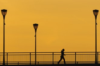 A jogger runs across the Old Bridge in Frankfurt am Main in the early morning shortly in front of