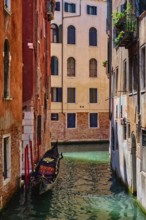 Narrow canal between colorful old houses with gondola boat in Venice, Italy, Europe