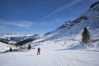 View of a ski resort piste with people skiing in Dolomites in Italy. Canazei, Italy, Europe