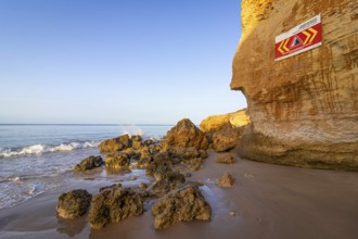 ROCKFALL UNSTABLE CLIFFS, KEEP A SAFE DISTANCE is written in English on a warning sign in Portugal