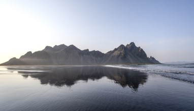 Black lava beach, sandy beach and sea, mountains Klifatindur reflected in the water, Eystrahorn and