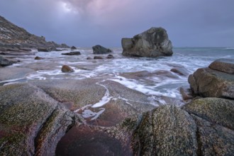 Rocks on beach of fjord of Norwegian sea in winter on sunset. Utakliev beach, Lofoten islands,
