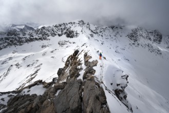 Mountaineer descending the narrow ridge of Piz Laviner, view of mountain panorama in wintry