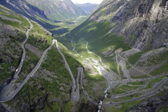 A winding road runs through a green valley between majestic mountains, Trollstigen, Andalsnes,