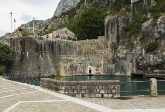 Tourists at the old stone fortifications of The Gurdic Gate or South Gate and pond in late summer,