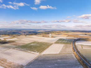 A sweeping view over snow-covered fields and a tower under a blue sky, district of Calw, Germany,