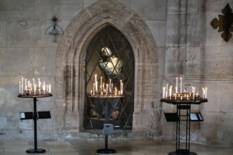 Sacrificial candles, behind them in the niche a figure of Jesus in the late Gothic hall church of