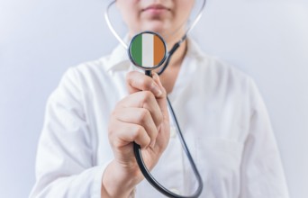 Female doctor holding stethoscope with Ireland flag. National health system of Ireland