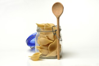 Conchiglione in glass jar with cooking spoon, Italian pasta variety