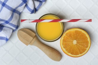 Orange juice in glass and orange, straw and citrus squeezer