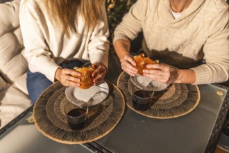Couple sharing a moment eating burgers and drinking, probably wine or soda, sitting at a table with