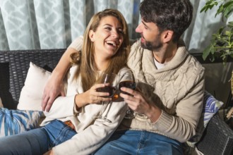 Romantic couple enjoying a relaxing evening together, sharing drinks and laughter on a comfortable