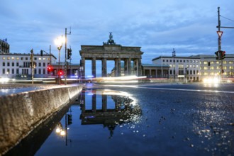 The Brandenburg Tor is reflected in a puddle, cars with lights switched on, Berlin, 27.01.2025,