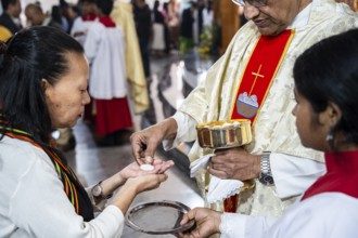 Devotees take holy communion from a priest during a Christmas day sermon on December 25, 2024 in
