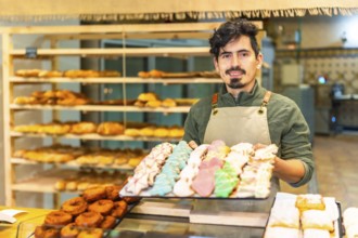 Portrait of a latin male artisan baker showing freshly baked Christmas cookies at shop