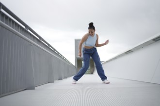 A woman in blue jeans is dancing on a white surface. Concept of freedom and joy as the woman