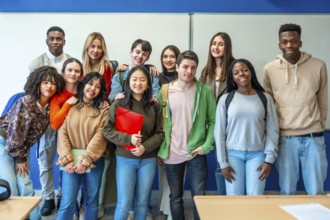Multi ethnic group of university students standing together in a classroom, sharing smiles and
