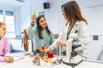 Female teacher assisting students during a chemistry experiment in a school laboratory, promoting