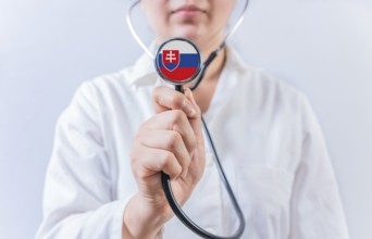 Female doctor holding stethoscope with Slovakian flag. National health system of Slovakia