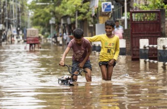 Children wade through a flooded street after heavy rains in Guwahati, India on April 28, 2025