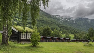 Cloudy forested ridges, wooden huts, Kirketeigen campsite, Kvam, upper Gudbrandsdal, Norway, Europe
