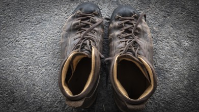 Close-up of worn leather hiking boots on dark ground, pilgrimage route Olavsweg or Olavsleden,