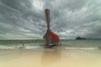 Longtail boat on the beach, dark rain clouds behind, Koh Ngai Island, Andaman Sea, Satun Province,