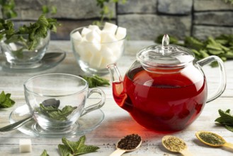 Touched teapot, glasses with mint, pieces of sugar and different types of tea on a table in front
