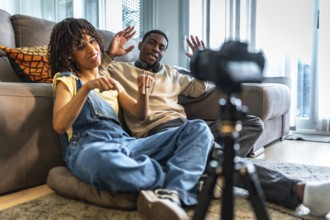 Two influencers recording a lively vlog in their cozy living room, gesturing enthusiastically and