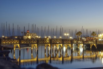 Evening atmosphere at the harbour with illuminated bridge and reflecting mast structures in the