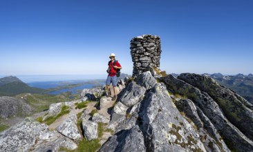 View of mountains and fjord landscape, mountaineer at the summit of Rundfjellet, Svolvaer,