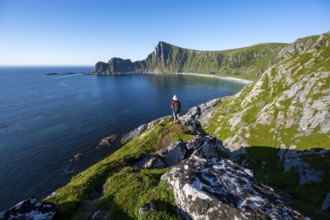 Mountaineer with view of coastal landscape, steep coast with peak Måtind, Høyvika beach and sea,
