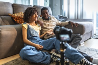 Two videomakers are creating content for their channel, discussing and smiling while recording a